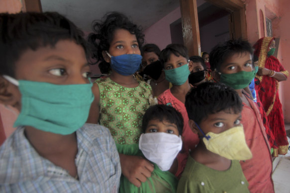 Evacuated children wearing masks as a precaution against the spread of coronavirus stand at a relief camp.
