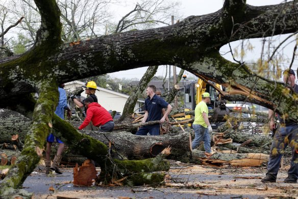 Police and firefighters get help from volunteers to clear downed trees after storms ripped through Sherwood, Arkansas.
