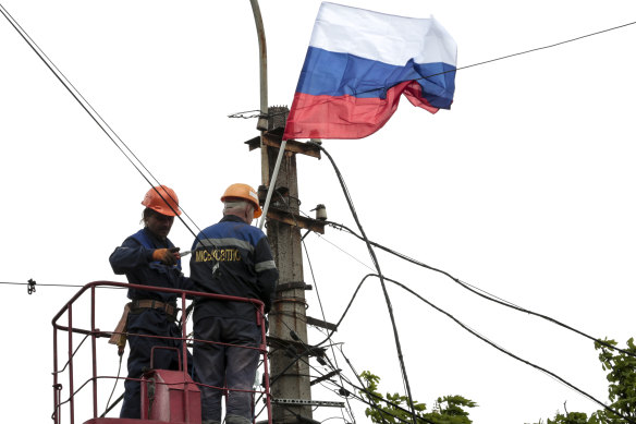 Municipal workers attach a Russian national flag to a pole preparing to celebrate 77 years of the victory in WWII in Mariupol,  Thursday, May 5, 2022.