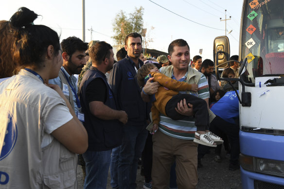 An aid worker at the Bardarash refugee camp carries a Syrian boy who fled with his family into Iraq.