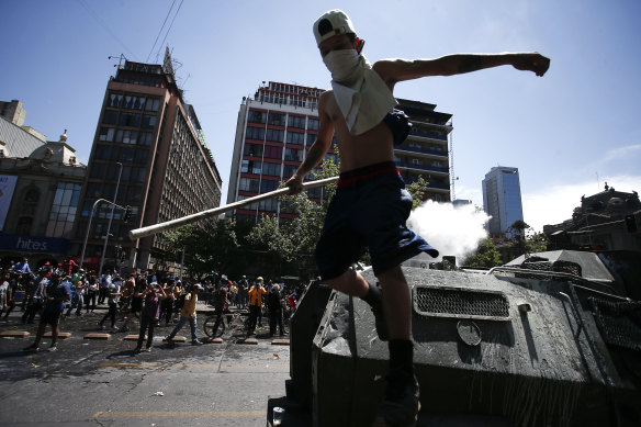 A demonstrator jumps off an armoured vehicle during the sixth day of protests in Chile.