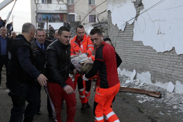 Rescuers carry an injured woman after a magnitude 6.4 earthquake in Thumane, western Albania.
