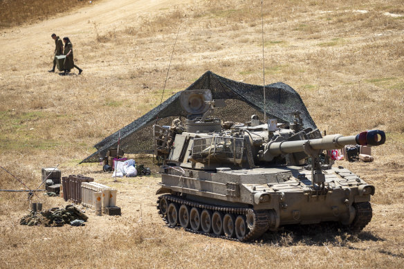 Israeli soldiers carry a box next to their mobile artillery piece.