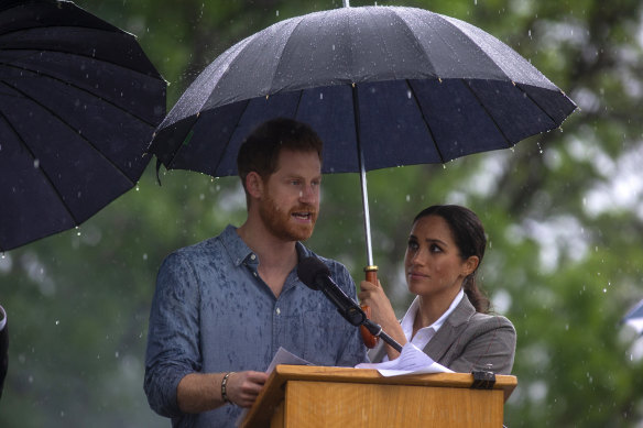 The Duchess of Sussex holds an umbrella for Prince Harry in Dubbo in 2018. 