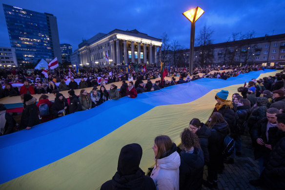 People carry a giant flag of Ukraine to demonstrate against Russian attacks in Ukraine at Independence Square in front of the Parliament Palace in Vilnius, Lithuania. 