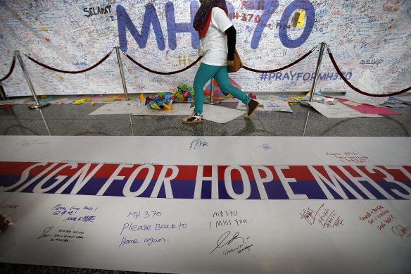 A woman walks past a banner filled with signatures and well-wishes for the missing Malaysia Airlines jetliner MH370 at the Kuala Lumpur International Airport in the days after the plane went missing.