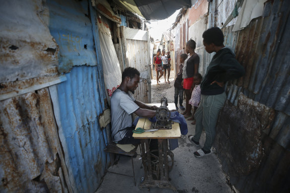 Poverty is fuelling discontent on the streets of Port-au-Prince, Haiti. Charles Lewis, 25, is pictured here repairing clothes.