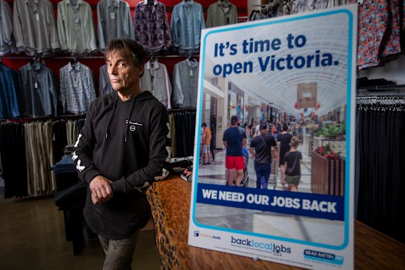 Mr Hutchinson with the poster calling on the state government to let businesses reopen.