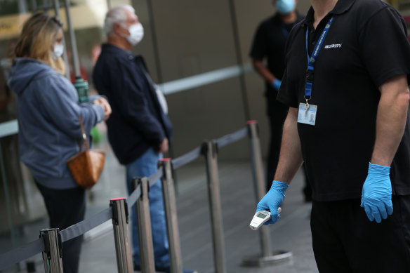 A security guard at the Bondi Junction Apple Store checks temperatures as customers line up.