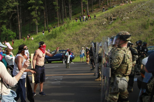 Protesters clash with a line of law enforcement officers in Keystone, SD, on the road leading to Mount Rushmore.
