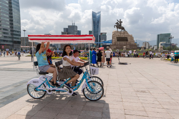 Young Mongolians enjoy riding a bicycle on the Sukhbataar Square.