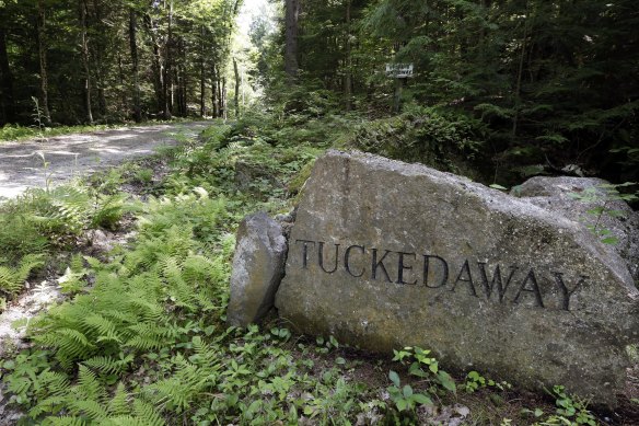 A boulder inscribed with "Tuckedaway" sits beside a road going to an estate in Bradford, New Hampshire, where Ghislaine Maxwell was taken into custody.