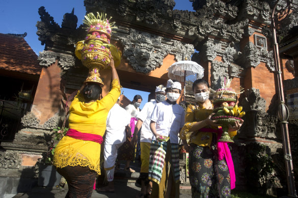 People wearing face masks as a precaution against coronavirus outbreak carry offerings during Hindu festival of Galungan in Bali, Indonesia.