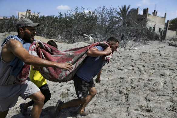 Palestinians evacuate a person from a site hit by an Israeli airstrike.