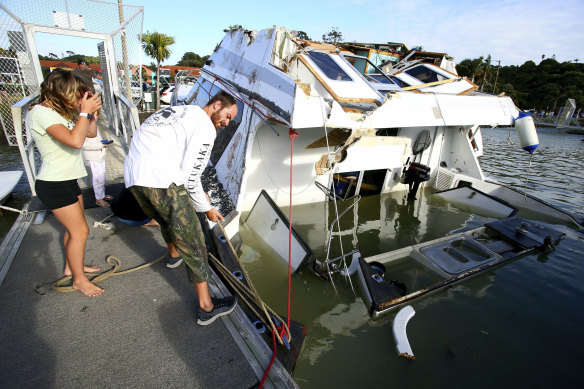 A couple look at a damaged boat in a marina at Tutukaka, New Zealand, on Sunday.