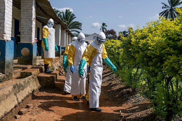 Gli operatori sanitari della DCR disinfettano il loro percorso dopo aver maneggiato il cadavere di una persona ritenuta morta di Ebola.