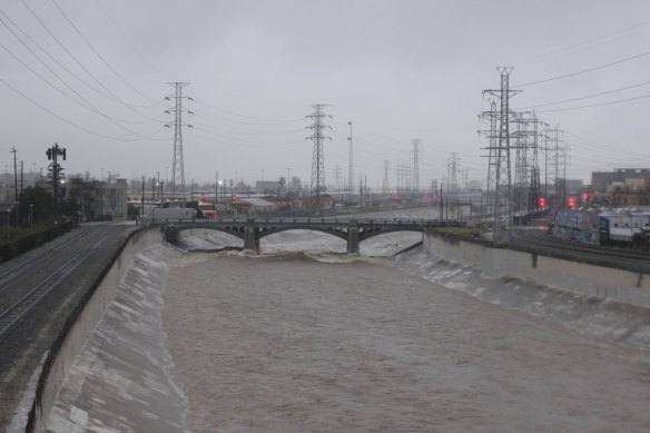 Sabato il fiume Los Angeles, bagnato dalla pioggia, scorre vicino al centro di Los Angeles.