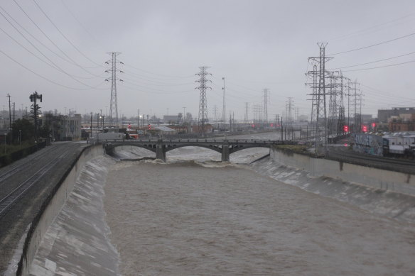 The rain-swollen Los Angeles River flows near downtown Los Angeles on Saturday.