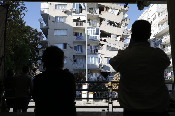Local residents look at a destroyed buildings in Izmir, Turkey, as rescue teams on continued to save people from the rubble. 