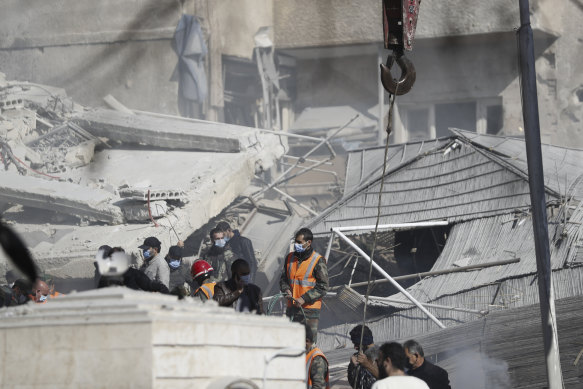 Emergency services work at a building hit by an airstrike in Damascus, Syria.