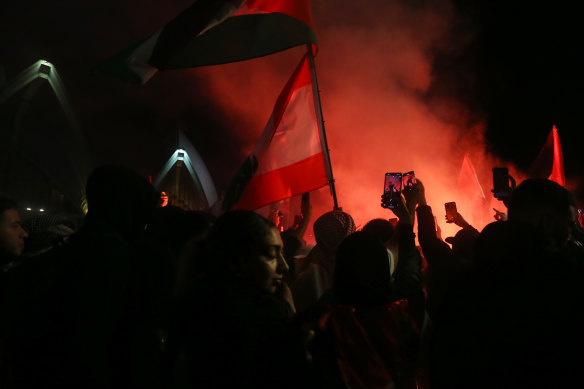 Palestine supporters ignite flares during a rally outside the Sydney Opera House.
