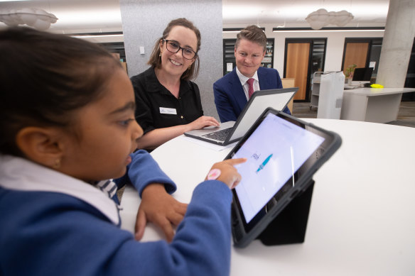 A Docklands student does the phonics check with teacher Bethany Tonkin (centre) and Education Minister Ben Carroll.