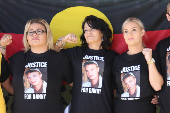 Danny Whitton’s mother and two sisters stand in front of an Aboriginal flag outside the NSW Coroners Court in February.