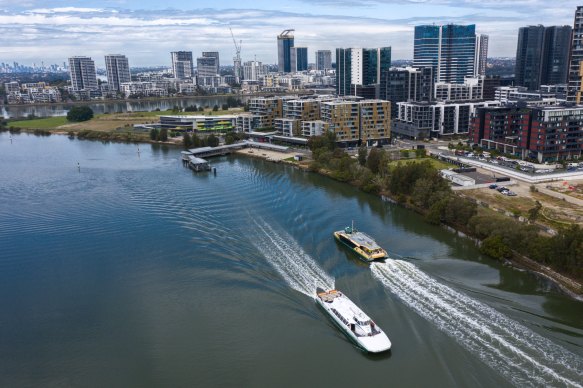 An older RiverCat ferry, left, passes a new RIver-class vessel on the Parramatta River on Tuesday.