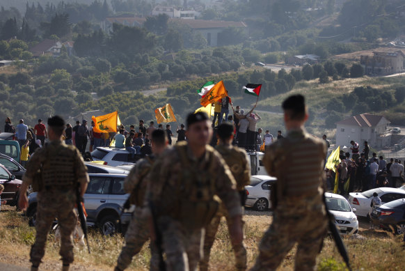 Hezbollah supporters, on the Lebanese-Israeli border near the Israeli settlement of Metula, wave Hezbollah, Iranian and Palestinian flags in solidarity with Palestinians.