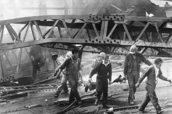 Westgate Bridge collapse, 1970: A victim is carried from a massive pile of twisted girders by civil defence men and workmates. 