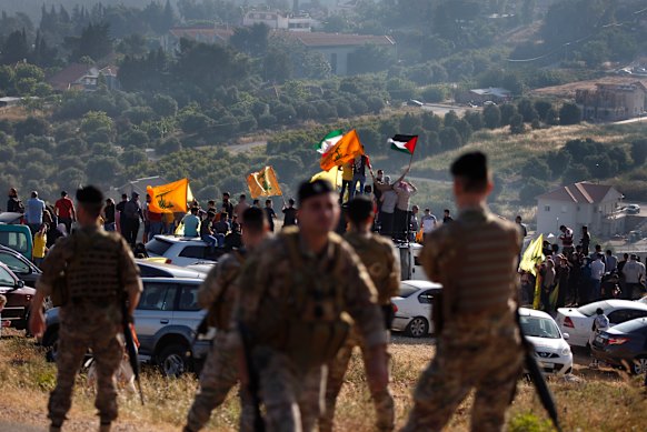 Hezbollah supporters wave their group, Iranian and Palestinian flags, in solidarity with Palestinians on the Lebanese-Israeli border near the Israeli settlement of Metula, background.