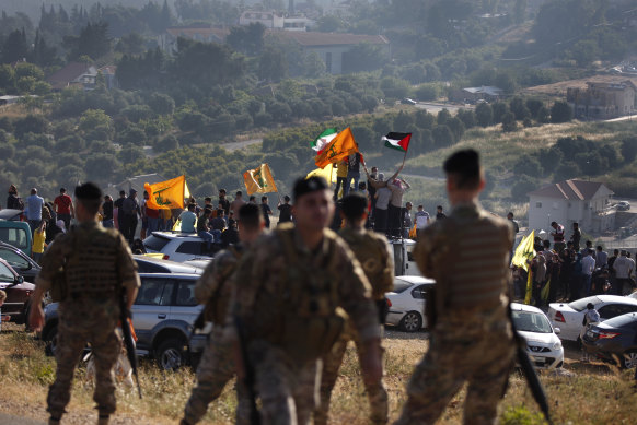 Hezbollah supporters wave their group, Iranian and Palestinian flags, in solidarity with Palestinians on the Lebanese-Israeli border near the Israeli settlement of Metula, background.