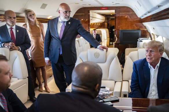 Walt Nauta, an aide to former president Donald Trump, standing left, listens as Trump speaks with reporters and staff aboard his plane Trump Force One on the way to Iowa on March 13.