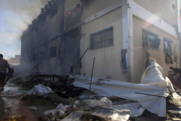 Palestinians try to extinguish a fire in the building of the UNRWA Vocational Training Center, which is used by displaced people as a shelter, after it was targeted by an Israeli tank shell in Khan Yunis.