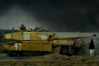 An Iraqi man stands in front of a British tank on the road from Basra to Baghdad in 2003.