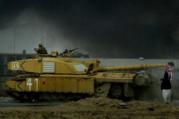 An Iraqi man stands in front of a British tank on the road from Basra to Baghdad in 2003.