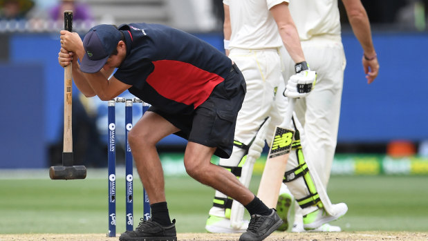 A groundsman tries to hammer some sense into the Boxing Day Test pitch.
