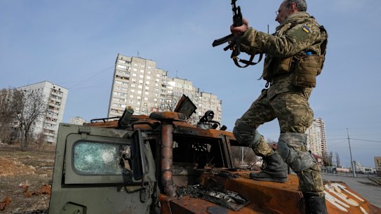 A Ukrainian soldier stands a top a destroyed Russian APC after recent battle in Kharkiv, Ukraine, March 26.