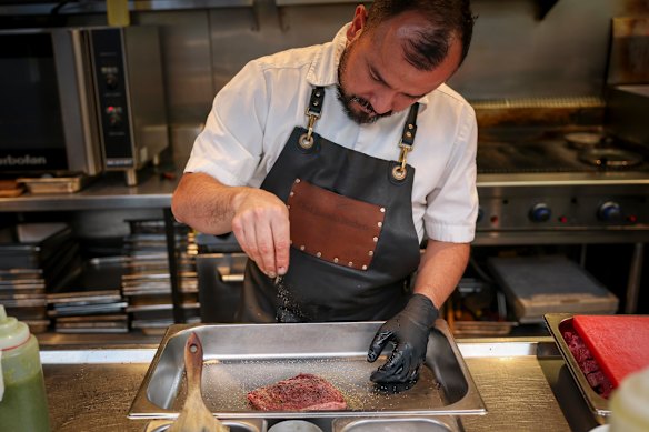 Berbeo temperando o bife antes de cozinhá-lo.