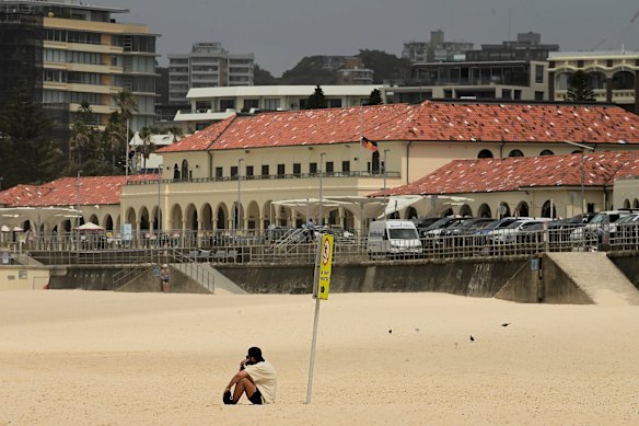 A man sits on Bondi Beach following last night’s mass shooting incident.