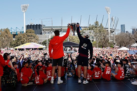 Opposing captains Dane Rampe and Lachie Neale show the premiership cup to hordes of fans at the parade.