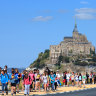 Tourists swamp France’s Mont Saint Michel.