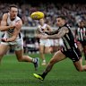Brennan Cox of the Dockers handballs under pressure from Jamie Elliott of the Magpies.