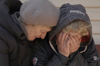 A neighbour comforts Natalya, whose husband and nephew were killed by Russian forces, as she cries in her garden in Bucha.