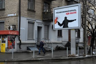 一個男人走過一個廣告牌，上面寫著“俄羅斯軍艦！ 在第聶伯羅的街道上去他媽的——你自己。
