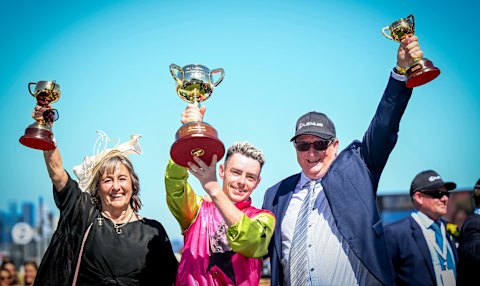 Jockey Robbie Dolan (centre) hoists the Melbourne Cup with trainers Sheila Laxon and John Symons.