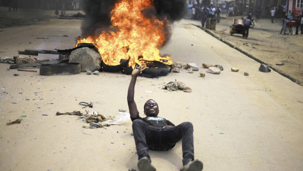 Protesters act in front of the camera after setting off a burning barricade in the Eastern Congolese town of Beni.