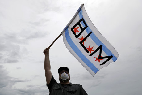A protester waves a city of Chicago flag emblazoned with the acronym BLM for Black Lives Matter. Protesters from the South Side were prevented from marching into wealthier areas.
