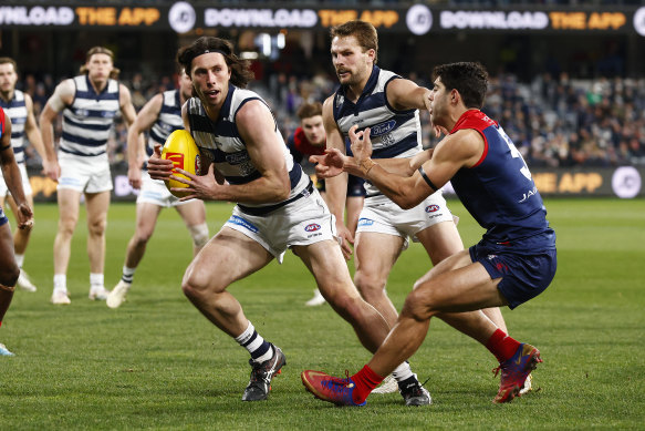 Geelong defender Jack Henry escapes the clutches of Melbourne’s Christian Petracca with support from teammate Tom Atkins.
