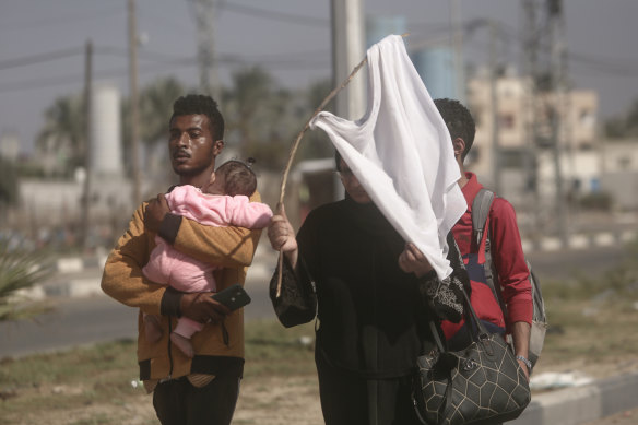 A woman holds-up a white shirt trying not to get shot as Palestinians flee Gaza City.